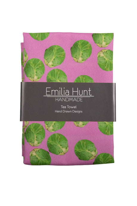 Folded tea towel with green and pink brussel sprout design with card band across centre showing Emilia Hunt Handmade logo