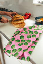 Load image into Gallery viewer, Pink sprout tea towel lying on kitchen worktop with man slicing bread in background

