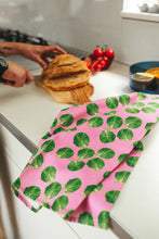 Load image into Gallery viewer, Pink sprout tea towel lying on kitchen worktop with man slicing bread in background